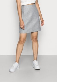 Grå utsvängd kjol av mjukt tyg, med en slät yta, mitt på låret längd, kombinerad med vita sneakers för en avslappnad look.