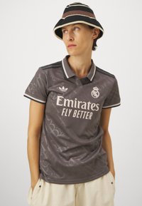 Sivi sportski polo s ovratnikom, s suptilnim tonovima uzorka, Adidas logotipom i natpisom "Emirates Fly Better" u svijetlom tekstu.