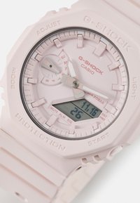 Casio G-SHOCK óra világos rózsaszín gyanta tok és szíjjal. Analóg és digitális kijelzőkkel, textúrált számlappal és ezüst kiegészítőkkel rendelkezik.