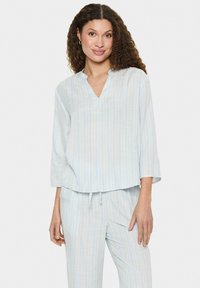 Top a righe blu chiaro e giallo con scollo a V e maniche a tre quarti, realizzato in un morbido tessuto texturizzato. Abbinato a pantaloni coordinati.