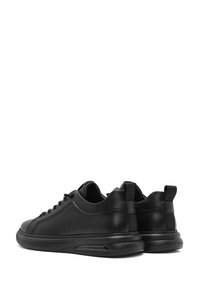 Sneakers neri in pelle con una finitura liscia, punta arrotondata, design con lacci, colletto imbottito e una suola spessa con ammortizzazione d'aria visibile.
