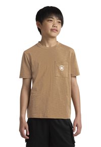 Trumpa rankovėmis marškinėliai, pagaminti iš minkštos medžiagos, su krūtinės kišenėle ir baltu apvaliu logotipu. Dėvimi su juodomis šortais.