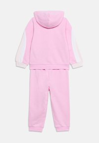 Ροζ παιδικό σετ φόρμας δύο τεμαχίων με φούτερ και παντελόνι, λευκές και ανοιχτό ροζ ρίγες στα μανίκια, ριμπ μανσέτες στους καρπούς και τους αστραγάλους.