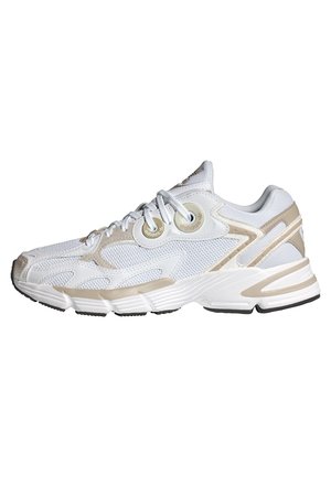 Hvid og beige Adidas sneaker med mesh-paneler, tyk sål, rundet tå og snørelukning vist fra siden.