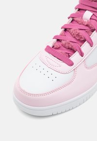 Sneaker featuring a white leather toe cap, pink synthetic side panels, textured pink laces, and perforation details on the front.