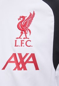 Κόκκινο κεντητό έμβλημα Liver bird με "L.F.C." πάνω από το κόκκινο λογότυπο του χορηγού "AXA" σε φόντο από άσπρο και μαύρο ύφασμα.