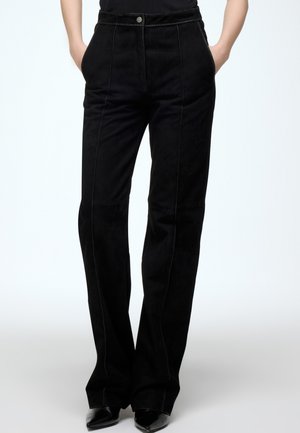 Black suede trousers with a straight fit, featuring side pockets, visible seams, and a front button closure. Minimalist design, smooth texture.