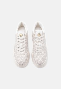 Ζευγάρι λευκά αθλητικά παπούτσια Michael Kors με μπεζ τύπωμα λογότυπου, λευκά κορδόνια και χρυσό έμβλημα MK στη γλώσσα, σε άποψη από ψηλά.