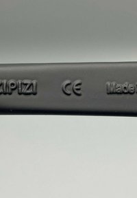 Czarny plastikowy pasek z wytłoczonymi napisami "KIPIZI", "CE" oraz "Made in" na gładkiej powierzchni, z matowym wykończeniem.