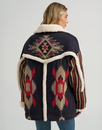 Flerfarget vevd jakke med et geometrisk mønster i rødt og krem, med en kremfarget faux fur-krage og stripete ermer.