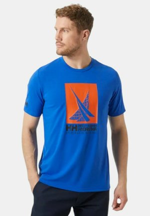 Camiseta azul hecha de tela suave, con un gráfico naranja que presenta un diseño de vela y texto negro. Cuello redondo y mangas cortas.