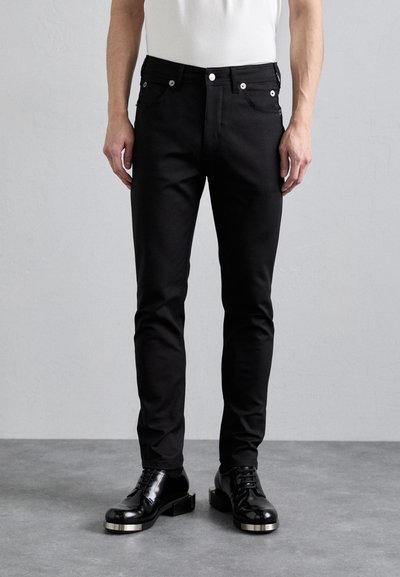 Černé džínové kalhoty slim fit s pěti kapsami, stříbrnými knoflíky a nýtovými detaily a hladkým matným povrchem.
