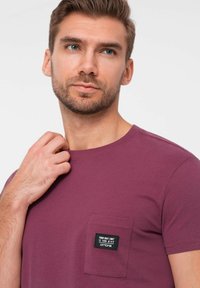 Lilla crew-neck t-shirt lavet af letvægts bomuld, med en lille lomme med et syet label med detaljer. Glat tekstur, korte ærmer.