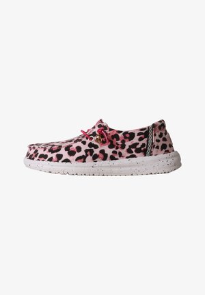 Chaussure décontractée slip-on à imprimé léopard rose et noir avec semelle blanche tachetée et lacets élastiques roses avec petit charm métallique sur le côté.