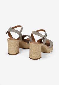Sandalias de tacón de ante gris con un amplio tacón de bloque texturizado y cinta ajustable en el tobillo. Diseño de punta abierta con una plantilla marrón suave.