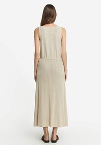 Ärmlös, beige, lång maxiklänning med en figursydd överdel och en flödande kjol, tillverkad av ett texturerat stickat tyg med en mjuk lyster.