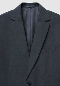 Dunkelgrauer Blazer aus strukturiertem Stoff, Einzelknopfverschluss, Schalkragen und eine Brusttasche. Das Innenfutter besteht aus glattem grauem Material.