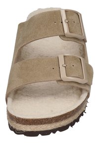 Beige suede sandal with two adjustable straps, soft inner lining, and sturdy brown sole featuring a textured surface for grip.