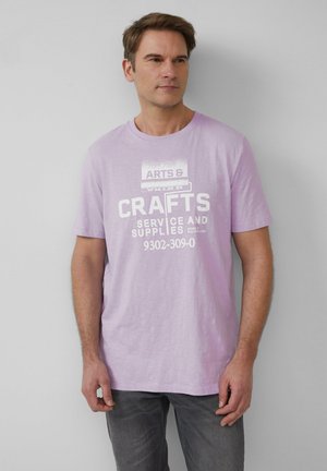 Lila katoenen T-shirt met een witte grafische print met de tekst "KUNST- EN HANDWERKSERVICE EN MATERIALEN". Korte mouwen en een ronde halsontwerp.
