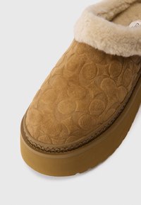 Karamelli suede libisemud alusjalad, millel on pehme kreemjas fliisist vooder, embosseeritud ringikujuline muster ja paks kummist tald lisamugavuse jaoks.