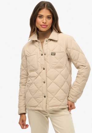 Beige gewatteerde jas met een kraag, twee voorzakken en drukknoopsluiting. Gladde textuur en ingetogen ontwerp.