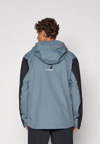 Water-resistant blue jacket with black accents, adjustable hood, and logo on the back. Smooth texture and relaxed fit.