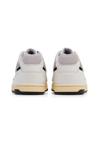 Hvite sneakers med grå detaljer og en svart stripe. Har en teksturert læroverdel, polstret krage og gummisåle.