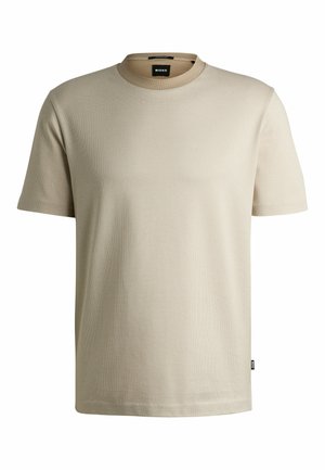 T-shirt beige à manches courtes en tissu texturé, avec un col rond et une petite étiquette sur le côté. Coupe classique et décontractée.