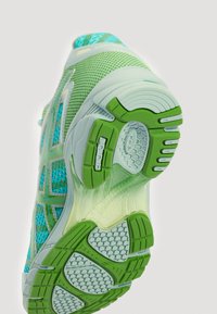 Sapatilha de corrida leve em rede aqua com detalhes verdes. Apresenta uma sola acolchoada com aderência texturizada e detalhes translúcidos.