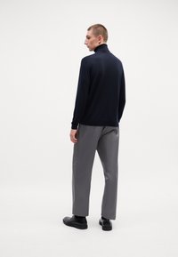 Tengerés turtleneck pulóver, puha tapintású, szürke, laza szabású nadrággal. Egyszerű dizájn minimális részletezéssel és fekete cipőkkel.