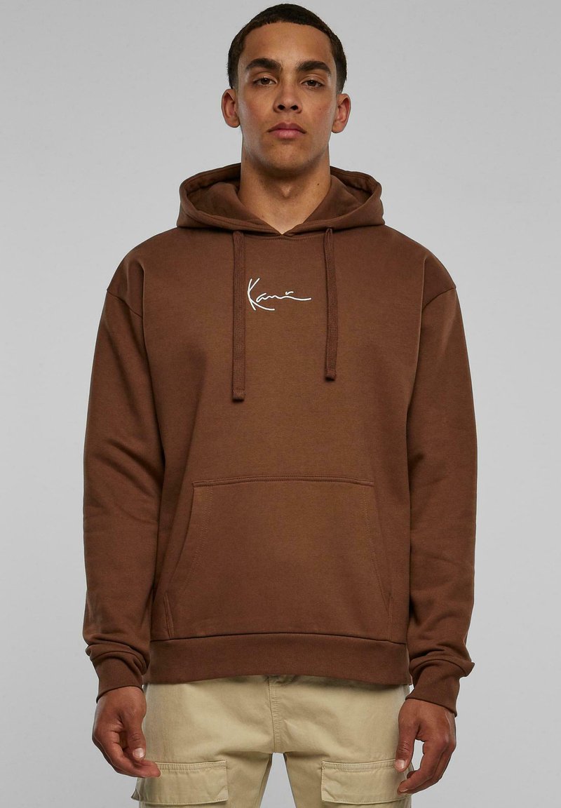 Felpa marrone con tasca frontale, cappuccio con coulisse e dettaglio del logo bianco sul petto. Tessuto morbido con polsini e orlo a costine.