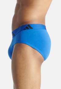 Blå kalsonger med ett svart elastiskt midjeband, prydda med tre svarta ränder. Tillverkade av mjukt tyg med en åtsittande design.