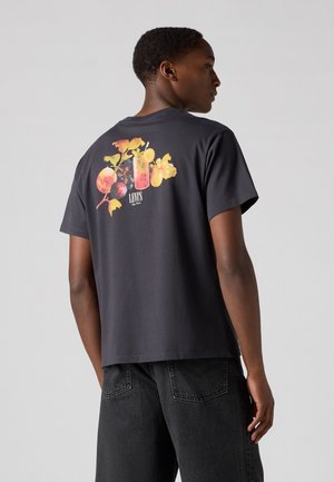 Camiseta de algodón negra con un gráfico de frutas coloridas en la parte posterior, mangas cortas y un corte relajado.