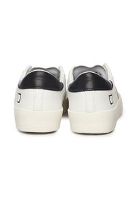 Witte sneakers met een zwarte leren hielkap. Gladde leren bovenkant, lichte rubberen zool en een minimalistisch ontwerp met een logo-detail aan de achterkant.