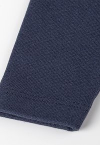 Tessuto lavorato a maglia blu navy con una texture liscia, caratterizzato da un orlo pulito e una leggera elasticità. Nessun motivo visibile o dettagli metallici.