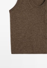 Brun stickad ärmfri topp med rund halsringning, fin textur och en diskret ficka på vänster sida.
