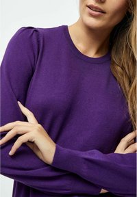 Lila Strickpullover mit langen Ärmeln, einem Rundhalsausschnitt und dezenten Puffdetails an den Schultern. Glatte Textur mit einer taillierten Silhouette.