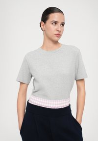 Camiseta de algodón gris con mangas cortas y cuello redondo, que presenta una cinturilla elástica de cuadro vichy rosa.