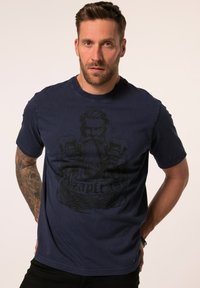 T-shirt in cotone blu navy a maniche corte, con una grafica di un uomo con barba e il testo "O'zapft Is" in nero. Tessuto liscio e vestibilità regolare.