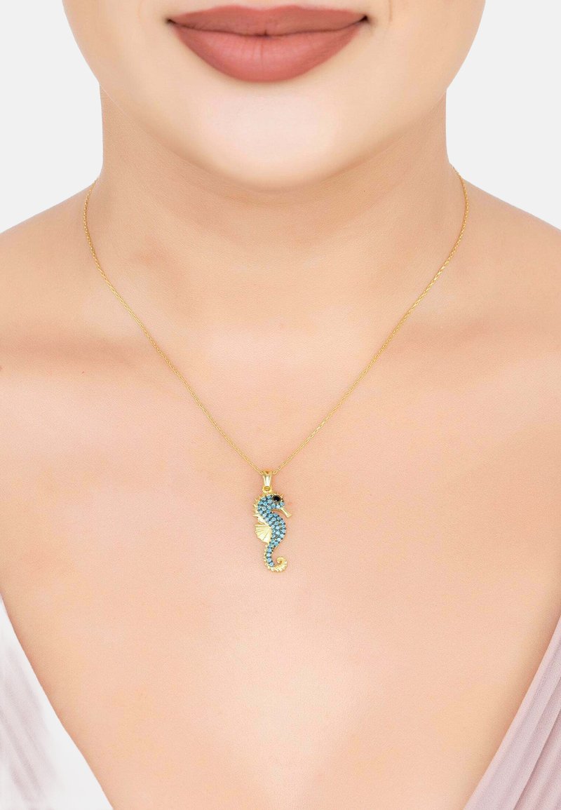Halskette aus goldfarbenen Ketten mit einem Seepferdchen-Anhänger, der mit blauen und schwarzen Strasssteinen verziert ist, detaillierten Flossen und einem eingerollten Schwanz.