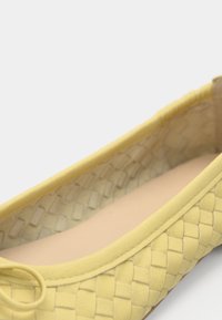 Κίτρινο πλεκτό δερμάτινο μπαλαρίνα με στρογγυλεμένη μύτη και μικρή λεπτομέρεια φιόγκου στο επάνω μέρος. Λείο εσωτερικό με απαλό υλικό.