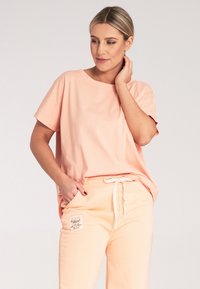 Koszulka bawełniana w kolorze brzoskwiniowym z okrągłym dekoltem i krótkimi rękawami, w zestawie z pasującymi spodniami dresowymi z metką i sznurkiem w pasie.