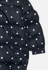 Laivastonsininen puhvitakki valkoisilla pilkuilla, jossa on kirjailtu malli, joustavat hihansuut ja sivutasku.