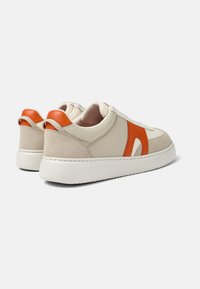 Zapatillas de cuero beige con acentos naranjas, detalles de ante y suela de goma blanca. Presentan cordones redondos y una textura suave.