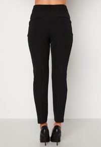 Svarta skräddarsydda byxor med slim fit, som har två bakfickor och en mjuk textur. I kombination med högklackade skor.