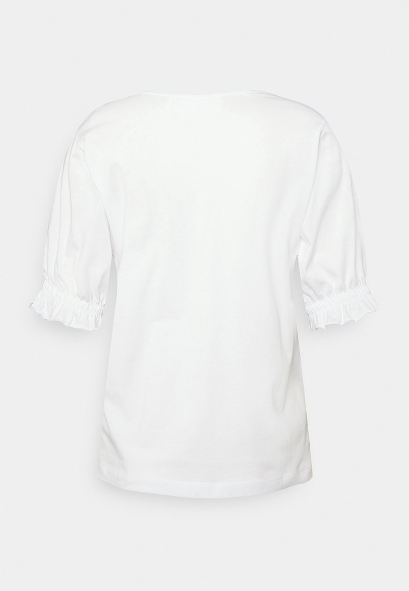 Chemise blanche à manches courtes avec poignets élastiqués froncés et ourlet droit, vue de dos sur un fond clair.