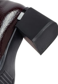 Elegante tomaia in vernice bordeaux lucida con tacco a blocco nero, superficie testurizzata e design a punta arrotondata. Suola in gomma nera con motivo antiscivolo.