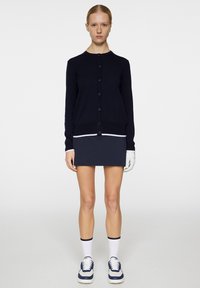 Takkia laivaston värissä, jossa on nappikiinnitys edessä ja kontrastiväriset valkoiset raidat helman kohdalla, yhdistettynä sopivaan laivaston väriseen minihameeseen ja tennareihin.