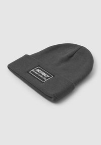 Szara dzianinowa czapka z wywiniętym mankietem, z prostokątną czarno-białą metką z napisem "DISTRICT" i "serce miasta."