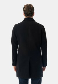 Cappotto di lana nero con una vestibilità su misura, maniche lunghe, spacco posteriore singolo e dettagli con bottoni sui polsini. Vista dal retro.